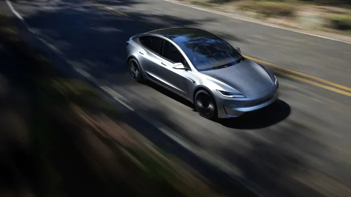 Coche eléctrico circulando a alta velocidad por una carretera secundaria rodeada de vegetación.