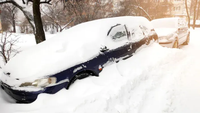 Automóviles completamente cubiertos por la nieve tras un fuerte temporal invernal.