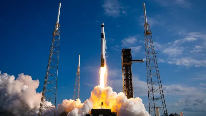 Cohete despegando desde una plataforma de lanzamiento con columnas y una gran nube de humo