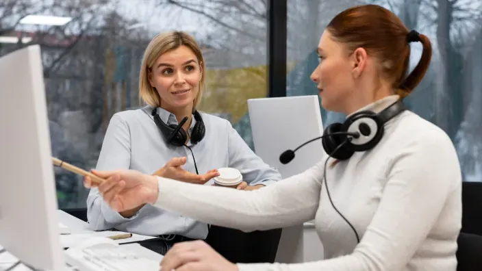 Supervisora formando a una nueva agente de atención al cliente en un call center. Apoyo y trabajo en equipo en la oficina.