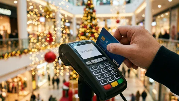 Mano pagando una compra de Navidad con una tarjeta de crédito VISA en un TPV. Pago contactless en un centro comercial.