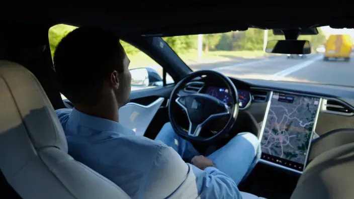 Conductor en el interior de un vehículo eléctrico con pantalla digital y sistema de navegación avanzado.