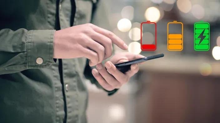Persona usando un smartphone con iconos digitales de niveles de carga para representar la autonomía de la batería del móvil.