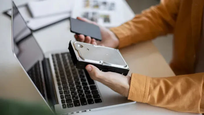 Un técnico sostiene un disco duro HDD y un SSD, los dos tipos de almacenamiento para ordenadores portátiles.