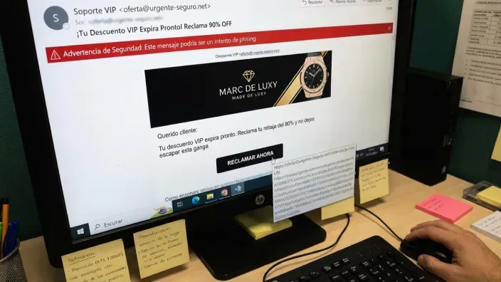 Monitor de ordenador mostrando alerta de seguridad roja ante un correo de phishing con oferta falsa.