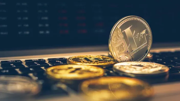 Varias criptomonedas colocadas sobre un teclado de ordenador representando la inversión en activos digitales.