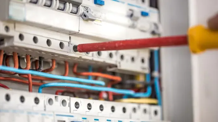 Cuadro eléctrico doméstico en proceso de reparación con destornillador.