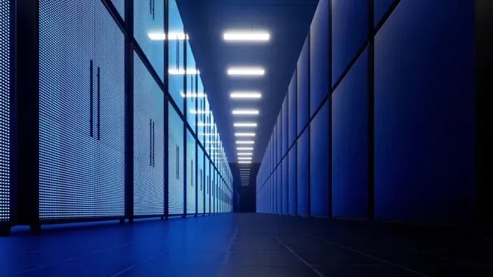 Pasillo iluminado de un centro de datos con racks de servidores y luces led azules.