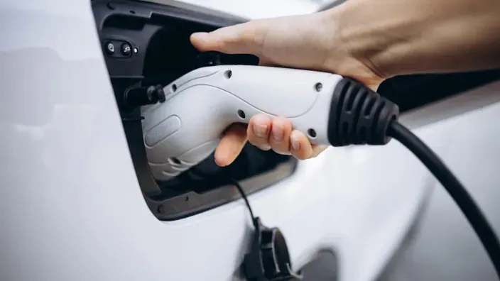 Primer plano del conector de carga enchufado a un coche eléctrico durante el proceso de recarga