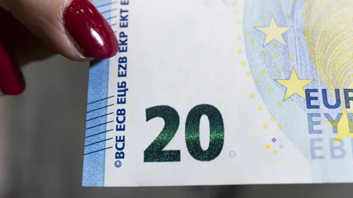 Detalle de un billete de 20 euros sostenido con los dedos, con el número 20 visible