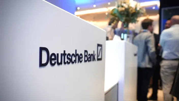 Mostrador de Deutsche Bank en un evento corporativo con asistentes al fondo.