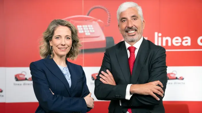 Directivos de Línea Directa posando frente al logotipo corporativo de la aseguradora en una oficina institucional.