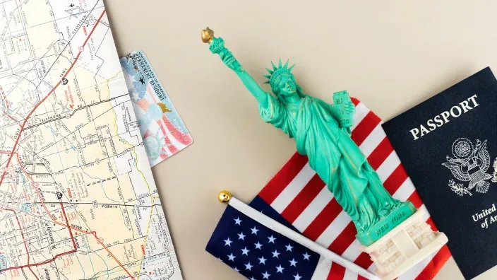 Planificación de un viaje a Estados Unidos: pasaporte, mapa, Green Card y una figura de la Estatua de la Libertad.