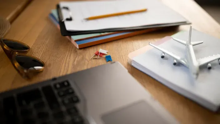 Escritorio de planificación de viajes con portátil, documentos y avión de juguete.