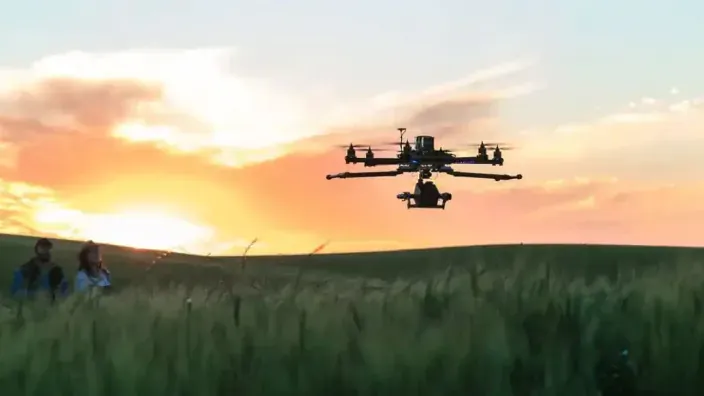 Dron profesional sobrevolando un campo de cultivo al atardecer para el análisis de datos agrícolas y tecnología geoespacial.