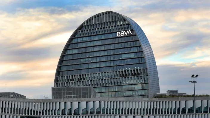 Sede corporativa de BBVA con arquitectura moderna y logotipo visible al atardecer.