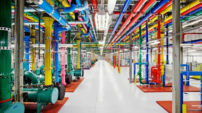 Interior de un centro de datos de Google con sus coloridas tuberías y servidores, la infraestructura que potencia la IA.