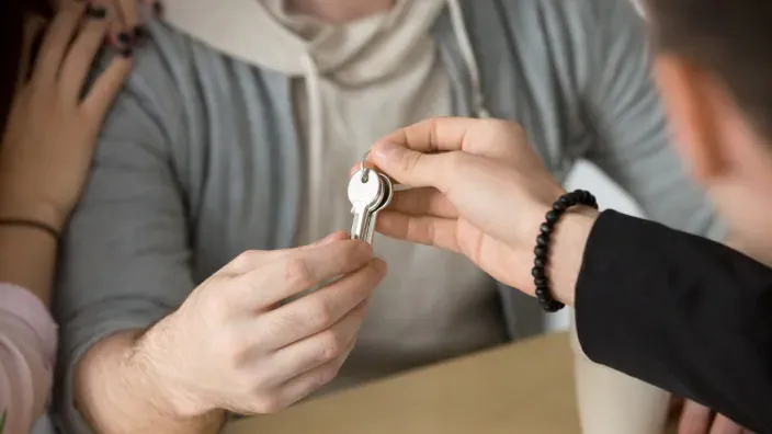 Agente inmobiliario o casero entrega las llaves de una casa a una pareja.