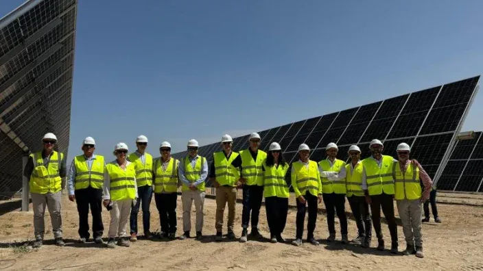 Grupo de directivos de Plenitude con chalecos reflectantes y cascos delante de paneles solares en Caparacena (Granada)