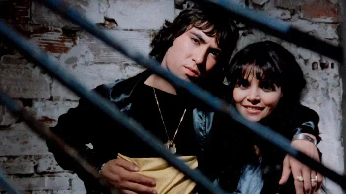 Fotograma de una película clásica española disponible en FlixOlé, con una pareja posando frente a una pared de ladrillo.