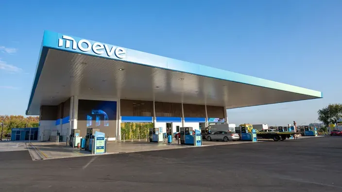 Detalle del rótulo con logotipo de Moeve en letras blancas sobre marquesina azul en gasolinera.