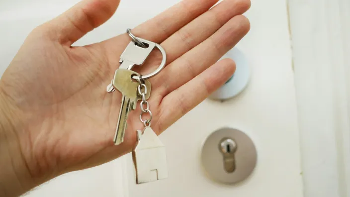 Llaves de una vivienda en una mano, símbolo de compraventa e hipoteca.