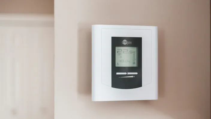 Termostato digital en la pared mostrando la temperatura interior de una casa