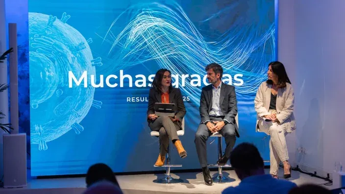 Tres personas sentadas en un escenario durante un evento corporativo de Sanitas