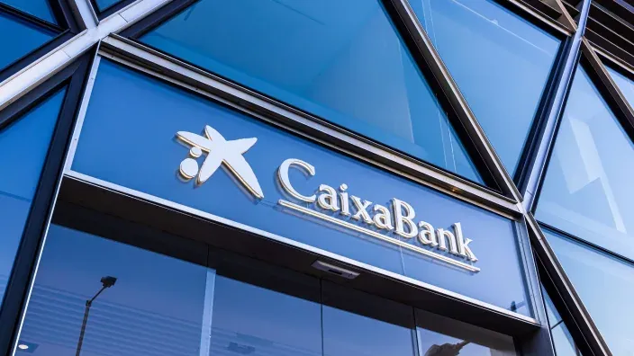 Fachada de una oficina de CaixaBank con su logotipo en la entrada principal.