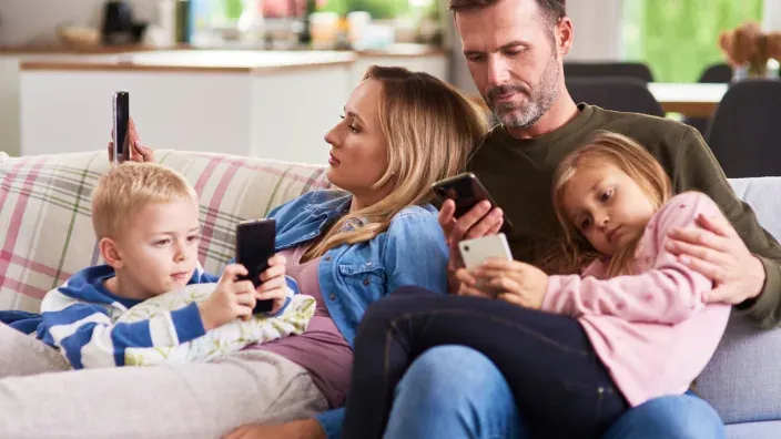 Familia en el sofá usando smartphones, representando el alto consumo de datos móviles y conectividad en el hogar.