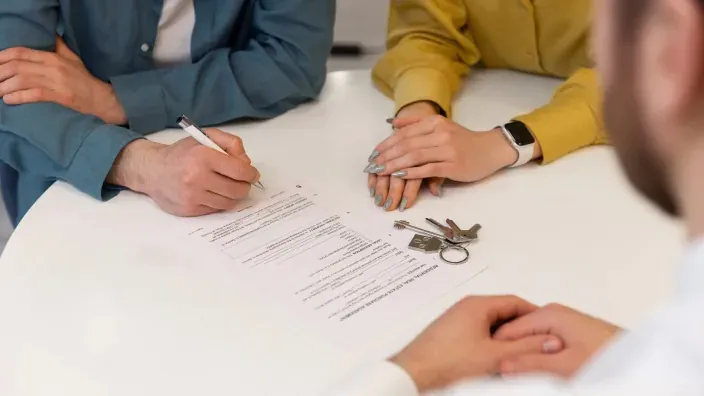 Pareja firmando el contrato de compra de una casa con un agente inmobiliario. Firma de la hipoteca y entrega de llaves.