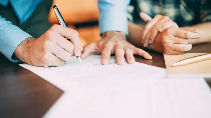 Primer plano de una mano firmando un contrato.