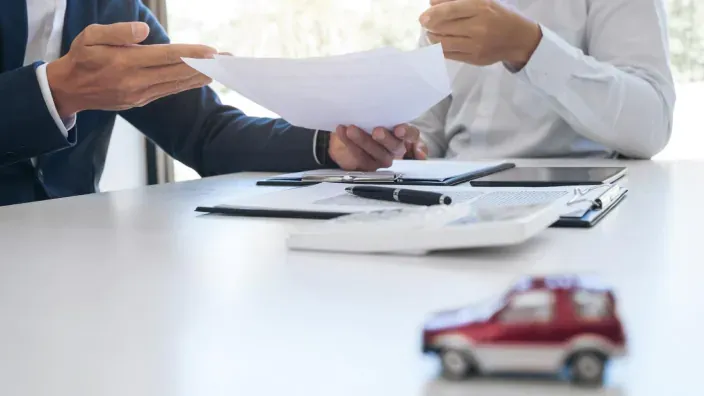 Asesor explicando los detalles de un contrato de seguro de coche a un cliente en una oficina profesional.