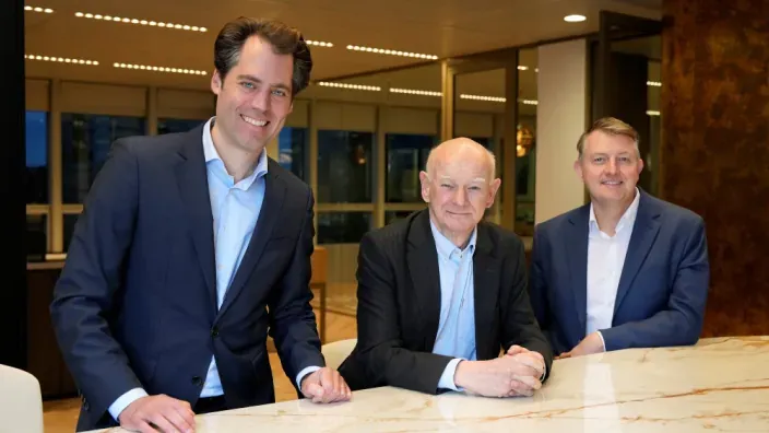 Floris Lugt, Howard Davies y Jan Sell, directivos de la empresa Qivalis sonriendo en una reunión en su oficina.