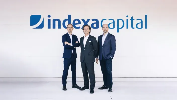 Los tres socios fundadores de Indexa Capital posan para una foto corporativa bajo el logotipo azul de la compañía de inversión.