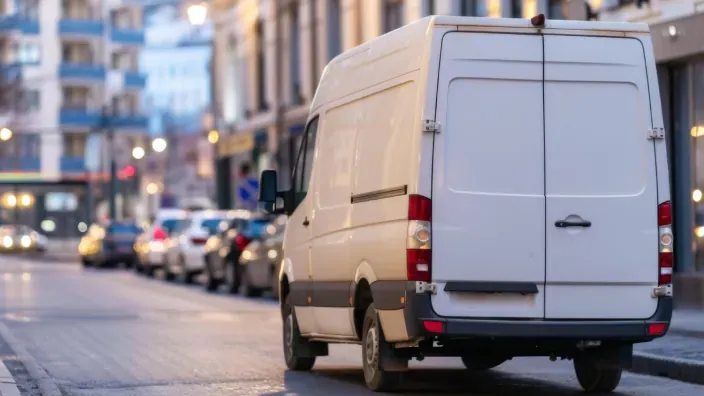 Furgoneta blanca circulando por una calle urbana