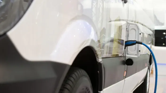 Furgoneta eléctrica conectada a un punto de carga, símbolo de movilidad sostenible.