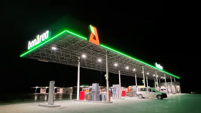 Estación de servicio BonÀrea iluminada por la noche con surtidores de combustible y zona de repostaje.