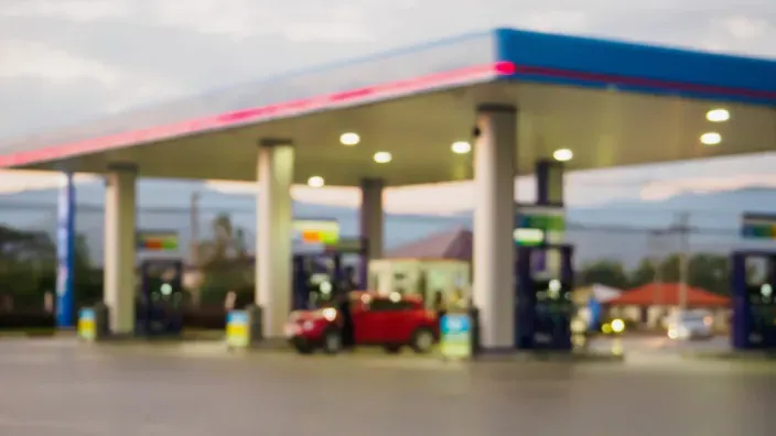 Gasolinera desenfocada con un coche rojo junto a los surtidores