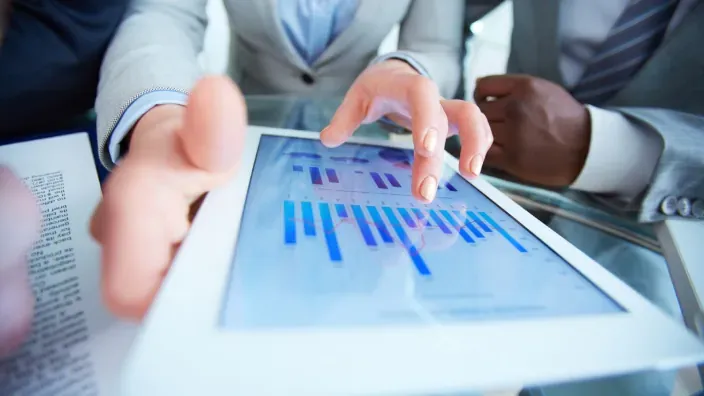 Profesionales analizando gráficos financieros en una tablet durante una reunión de trabajo