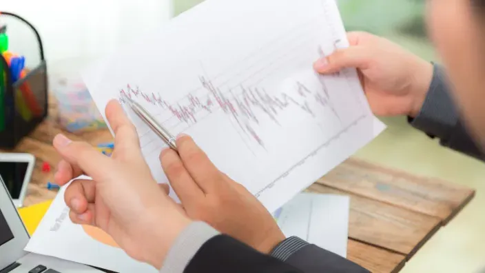 Asesores financieros analizando un gráfico bursátil de rentabilidad e inversión en una reunión de negocios.