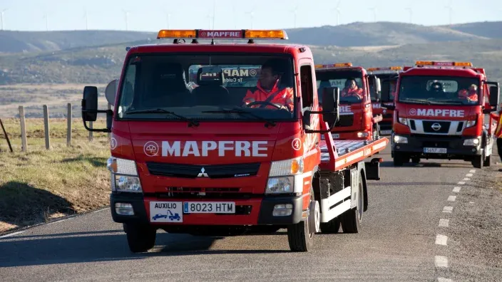 Flota de grúas de asistencia en carretera de MAPFRE circulando en una carretera.