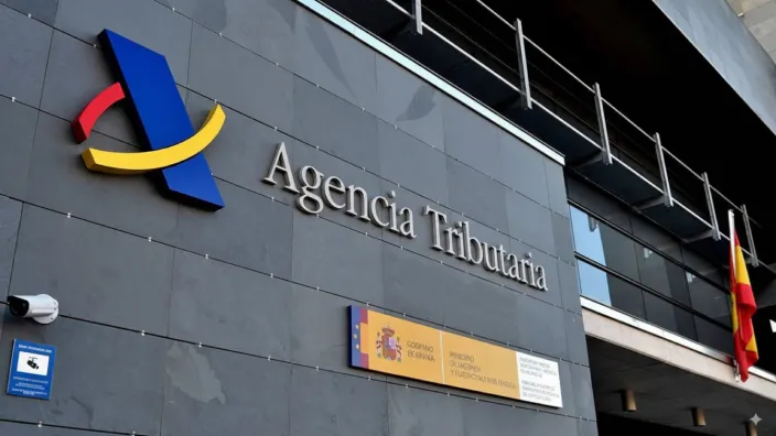 Fachada de una oficina de la Agencia Tributaria con el logo del Ministerio de Hacienda y la bandera de España.