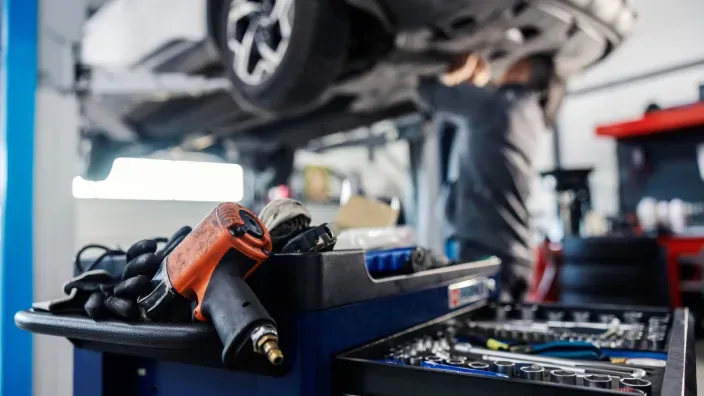 Herramientas de taller en primer plano con un coche elevado al fondo