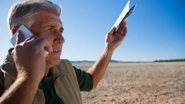 Agricultor preocupado intentando conseguir cobertura móvil en el campo.