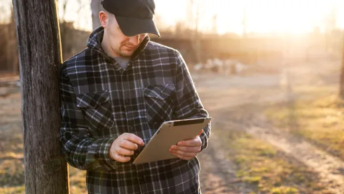 Hombre utilizando una tablet en una zona rural al aire libre.