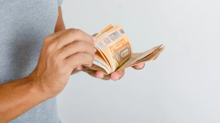 Hombre contando fajo de billetes de euro en efectivo para gestión de ahorro o pagos.