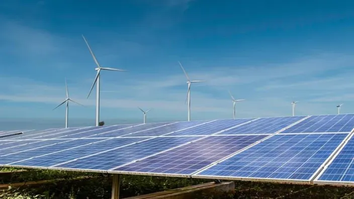 Cubierta industrial equipada con paneles solares fotovoltaicos junto a complejo energético al fondo.