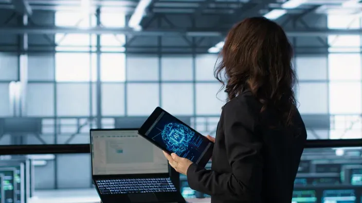 Mujer con tablet de inteligencia artificial en un centro de datos para representar la gestión tecnológica y el big data.