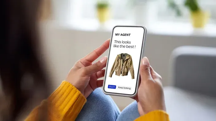 Persona usando una app de compras con recomendaciones de inteligencia artificial en el móvil junto a iconos digitales de comercio electrónico.